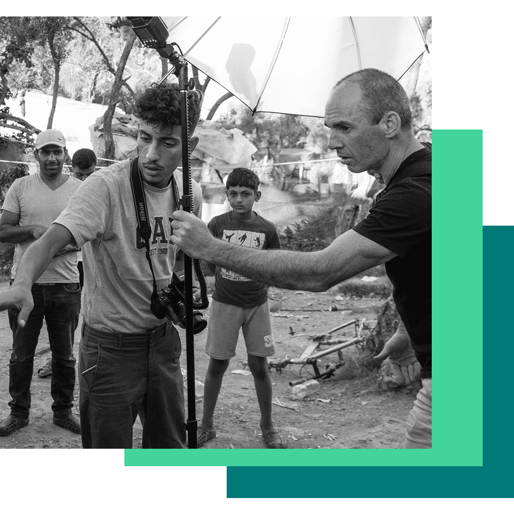 ein Fotograf wird von seinem Assistenten dabei unterstützt, Fotos von Flüchtlingen zu machen